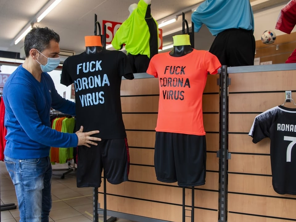 Ein Mitarbeiter eines Sportartikelladens stellt T-Shirts aus