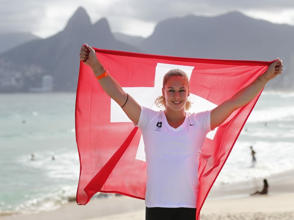 Giulia Steingruber posiert 2016 mit der Schweizer Fahne am Strand von Rio de Janeiro.