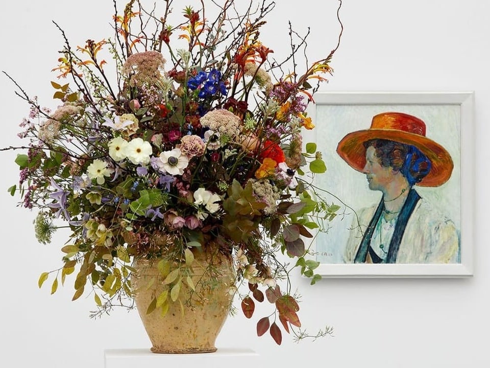Gemälde einer Frau mit Hut, davor eine beige Blumenvase mit einem Blumenstrauss.