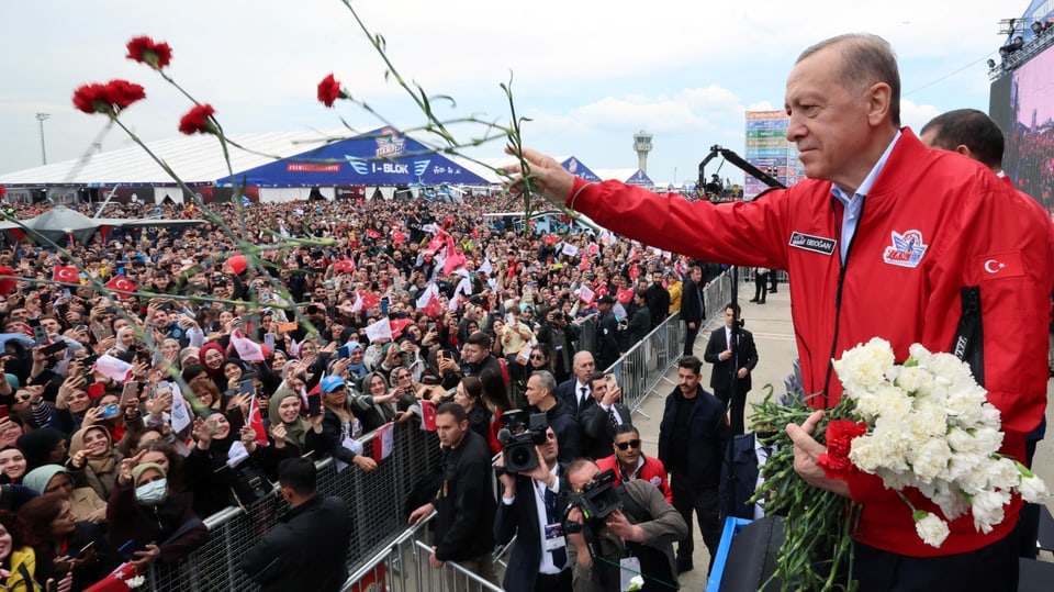 Man throws flowers into the crowd.