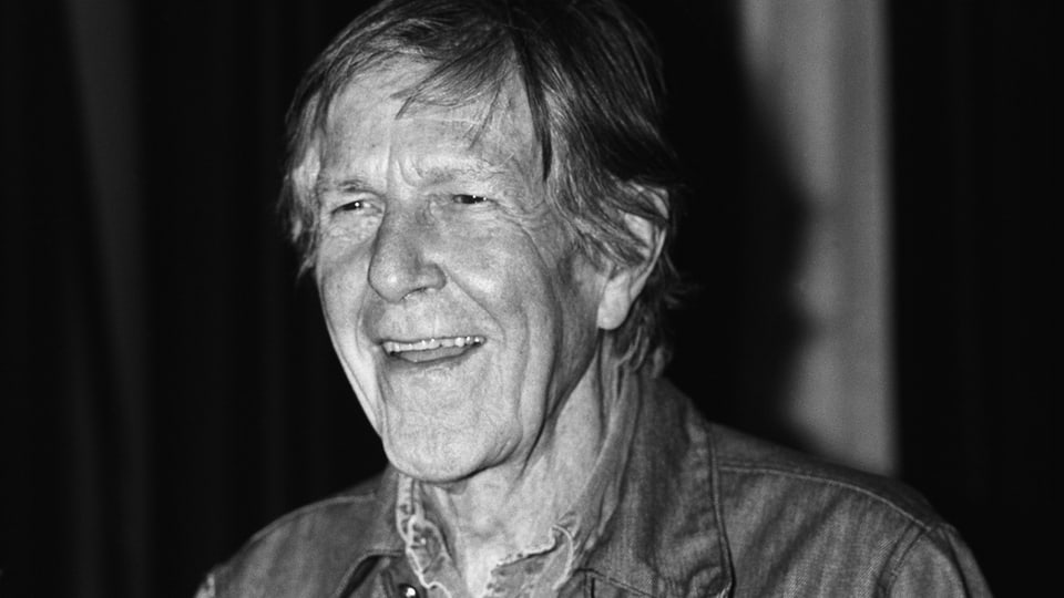 Schwarz-weisse Portraitaufnahme von einem lachenden John Cage.