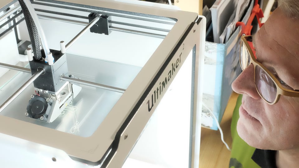 Ein Ultimaker 2 3D-Drucker, Christoph Laimer guckt hinein.