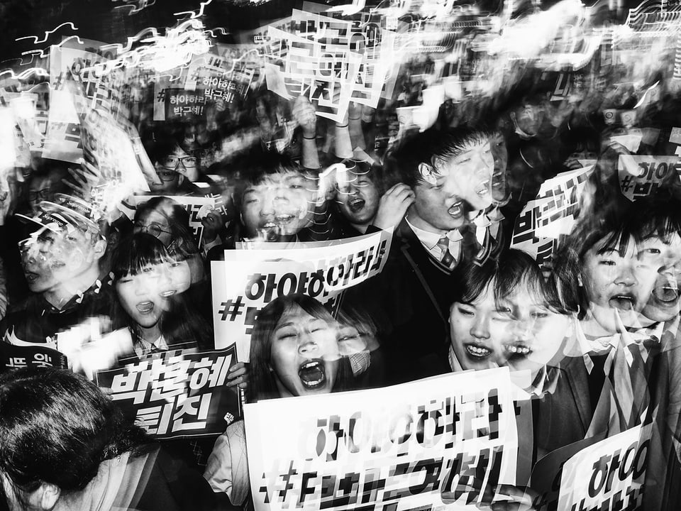Ein verschwommenes schwarz-weiss-Bild zeigt schreiende Studenten mit Plakaten in den Händen.