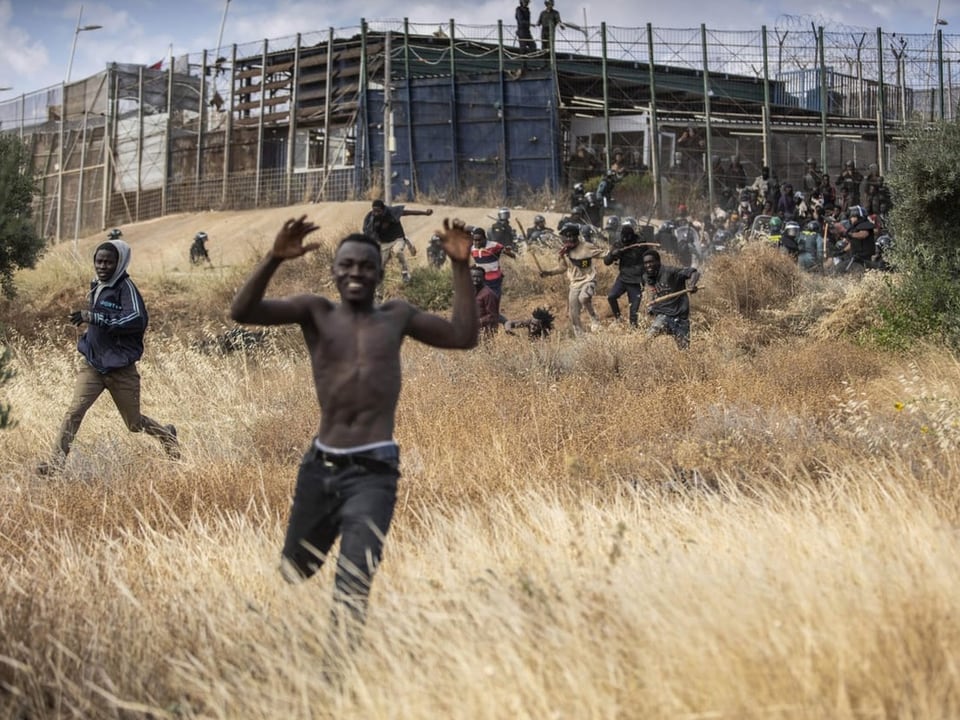 Ein Migrant jubelt, nachdem er den Grenzzaun überquert hat.