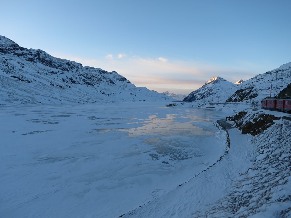 Das Bild zeigt einen zugefrorenen Bergsee inklusive Zug auf dem Bild. 