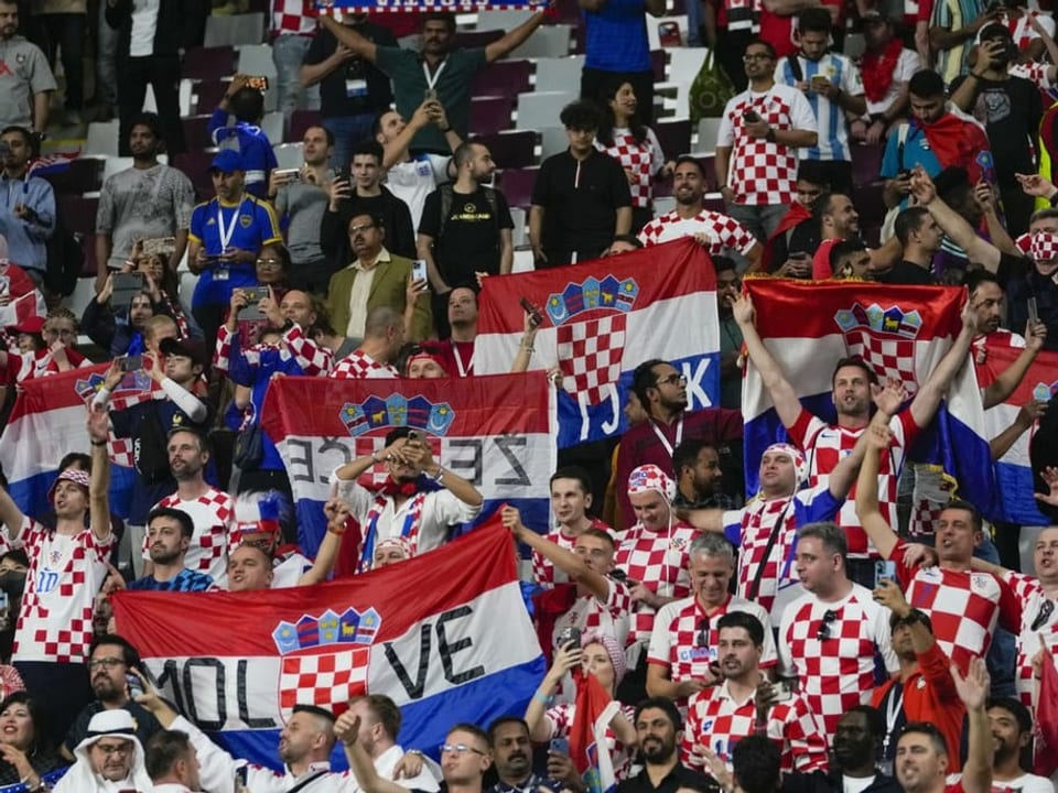 Kroatische Fans feiern mit Flaggen ihr Team auf der Tribüne.
