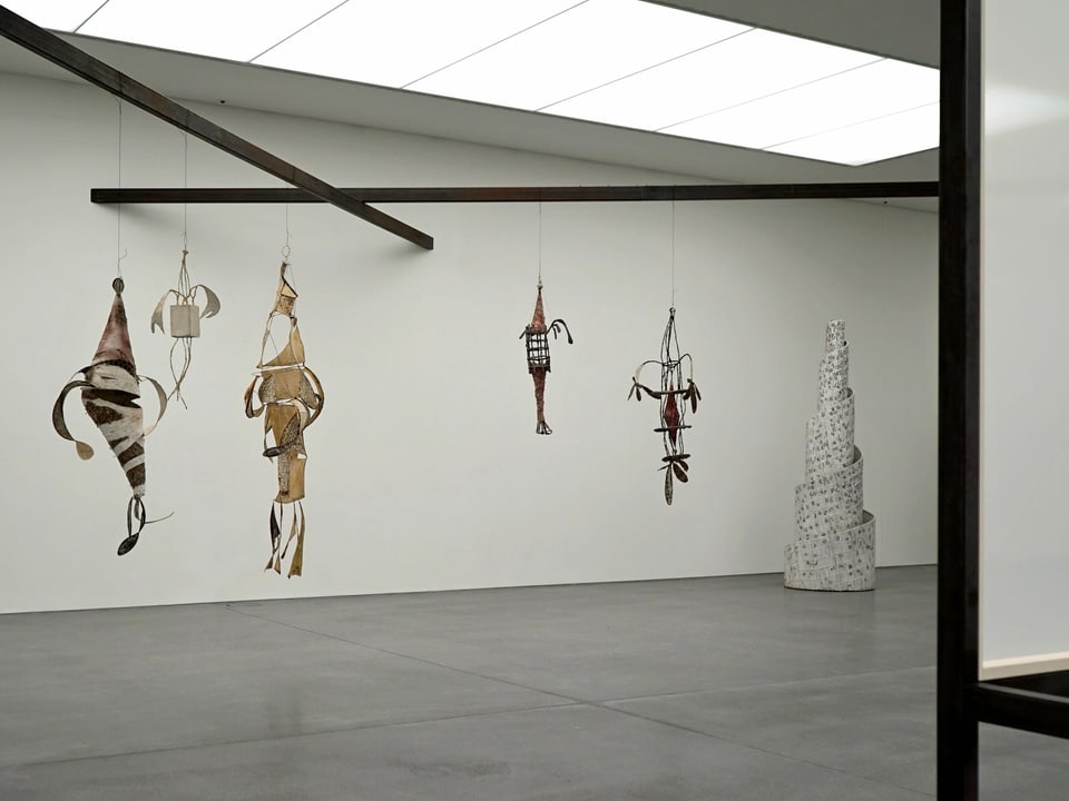 An Stangen hängen Kunstobjekte.