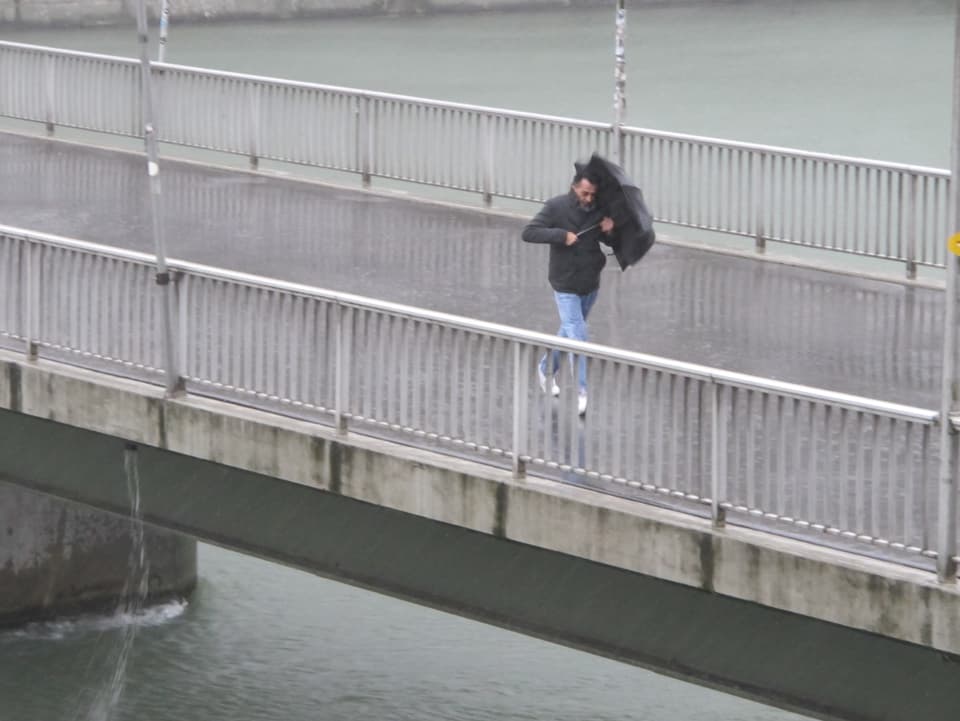 Mann mit Schirm auf Brücke