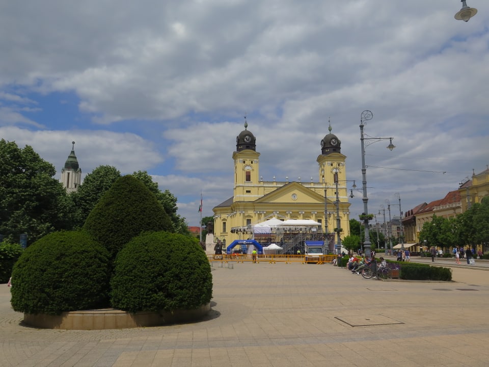 Ein Platz in der Stadt Debrecen. Im Hintergrund eine Kirche. Auf dem Platz hat es geschnittene Büsche.