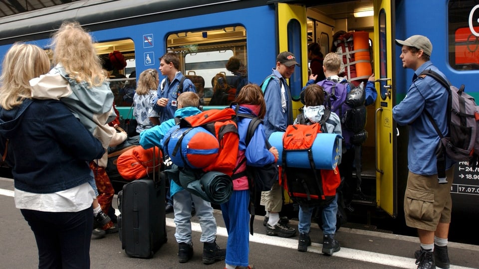 Kinder mit Rucksäcken besteigen einen Zug der SBB.