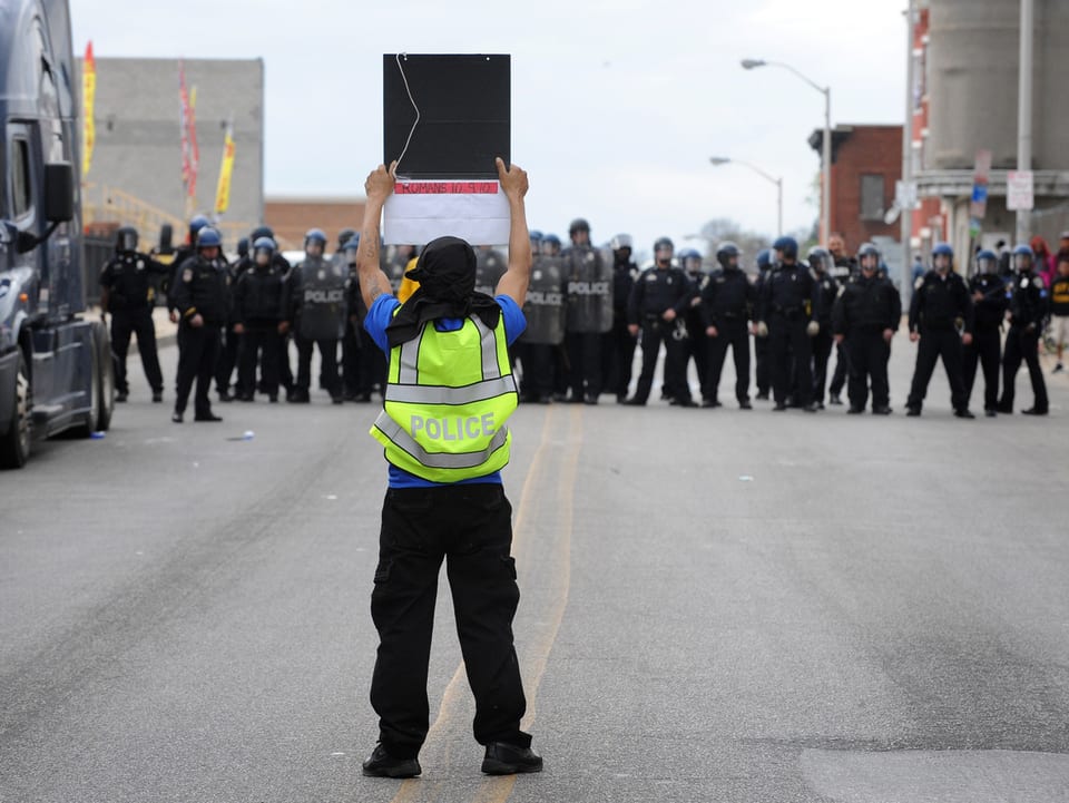 Ein Aktivist stellt sich demonstrierend vor eine Reihe Polizisten. 