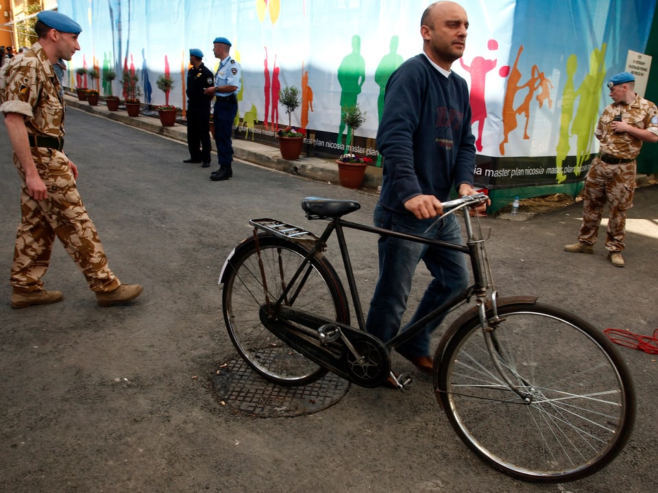 Ein Fahrradfahrer passiert zwischen zwei UN-Soldaten in Nikosia.