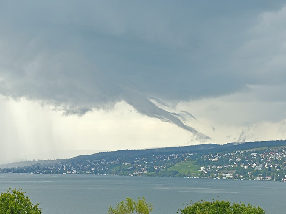 Eine, von einer Gewitterwolke ausgehende schlauchartige Wolkenfahne hängt über dem Zürichsee.