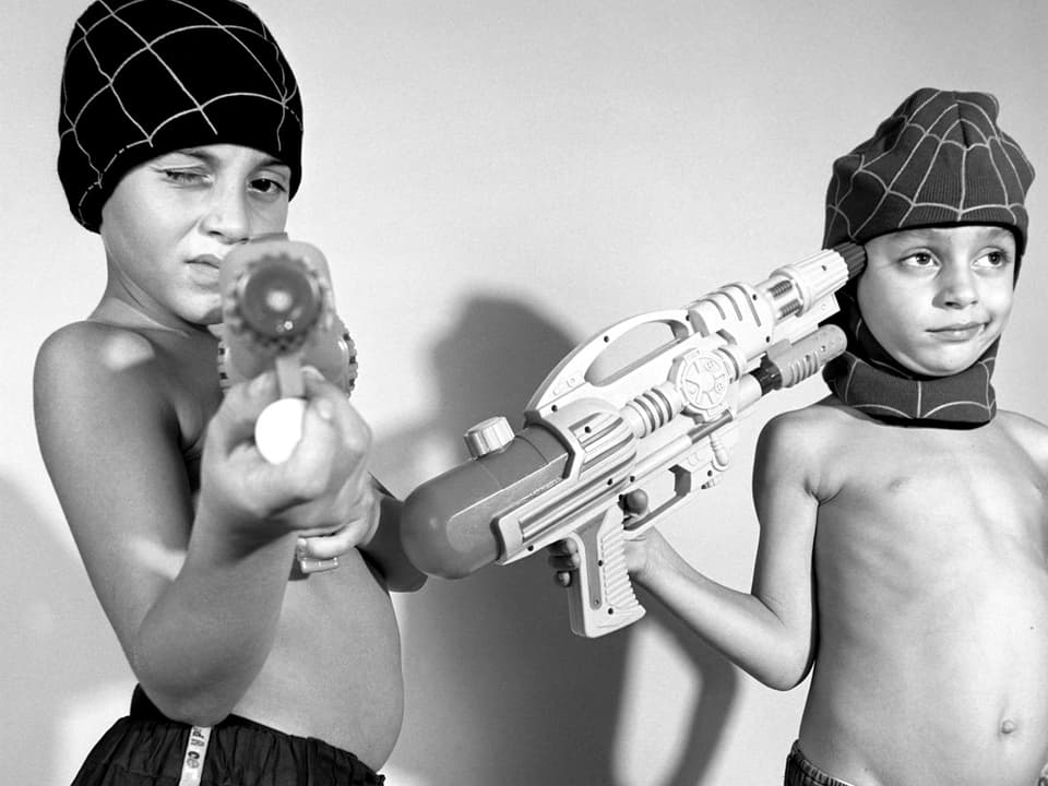 Zwei Jugendliche mit Wasserpistolen und Mütze