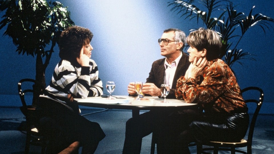 Interview-Situation mit drei Personen, die an einem Tisch sitzen