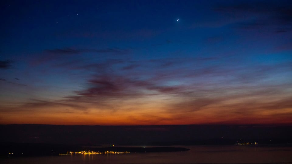 Heller Punkt im blauen Nachthimmel über Horizont mit Abendrot.