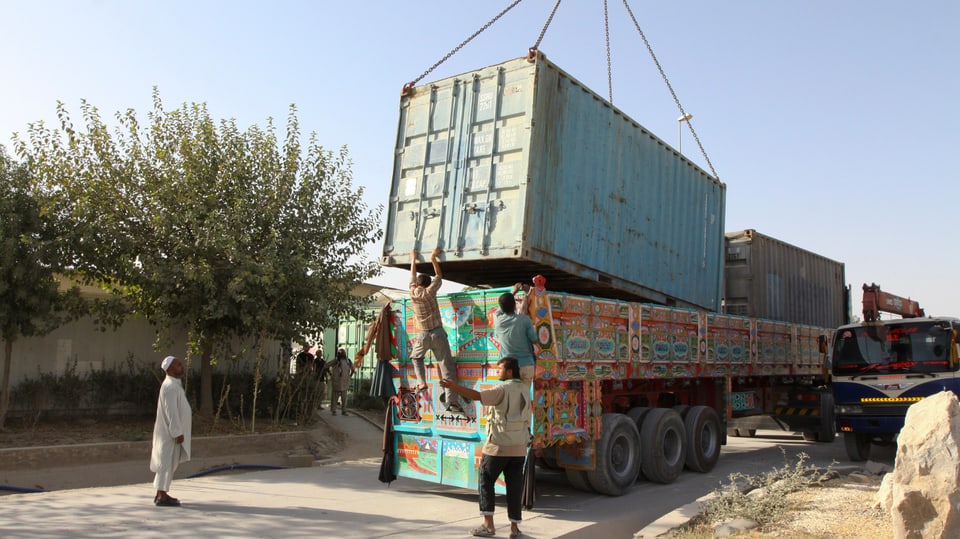 Afghanische Helfer verladen einen MIlitärcontainer der Bundeswehr auf einen Lastwagen