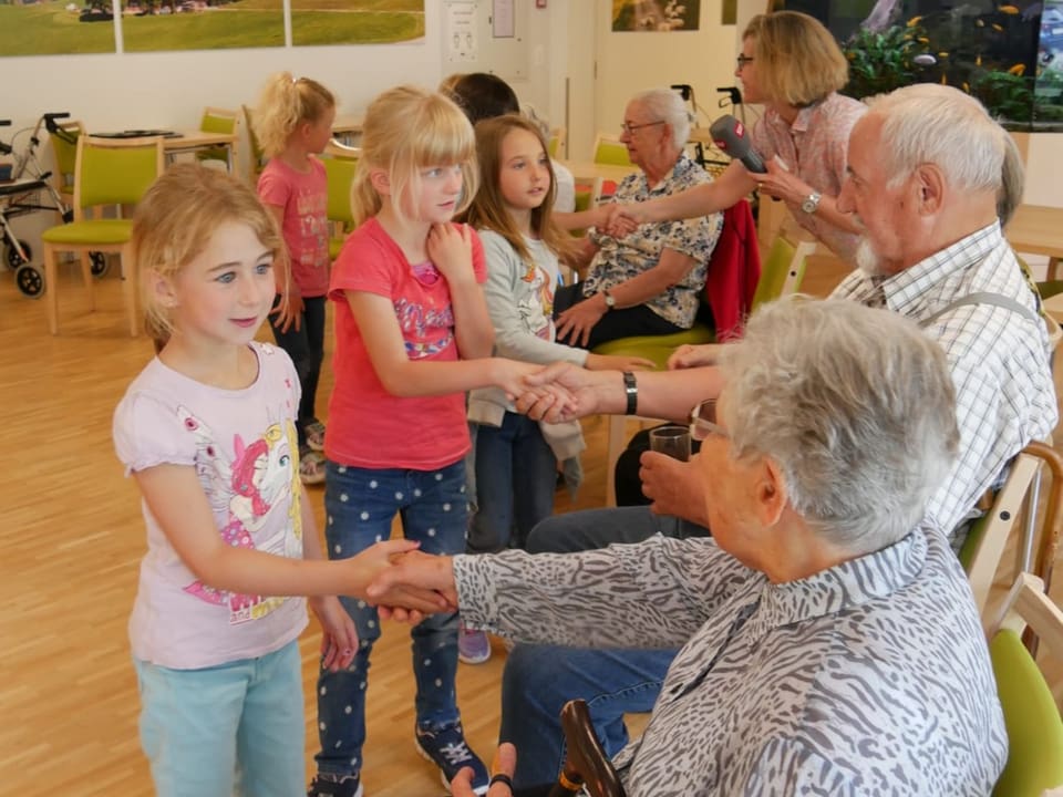 Kinder und Senioren schütteln sich zum Abschied die Hände.