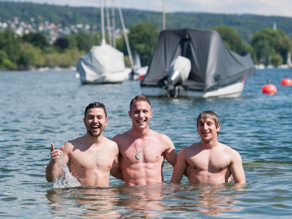 Zu sehen sind drei junge Männer, die im Zürichsee posieren.