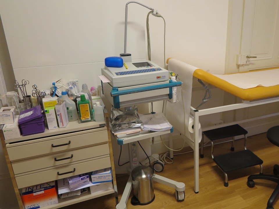 Ein Behandlungszimmer in einer Arztpraxis mit vielen Geräten.