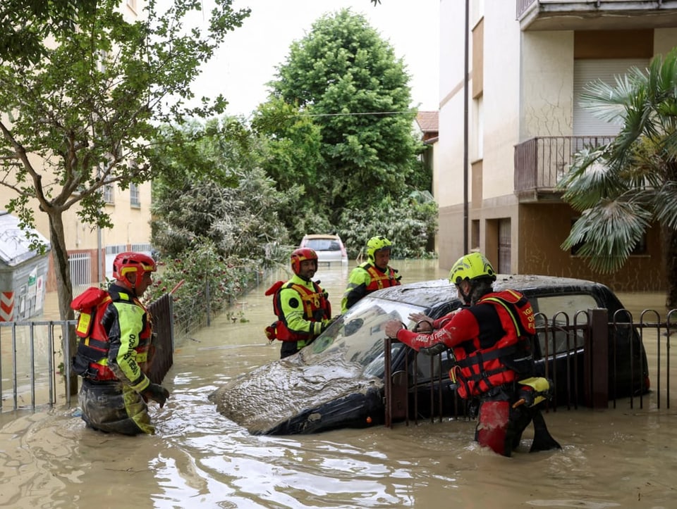 Feuerwehrleute arbeiten neben einem überfluteten Auto in Faenza. 