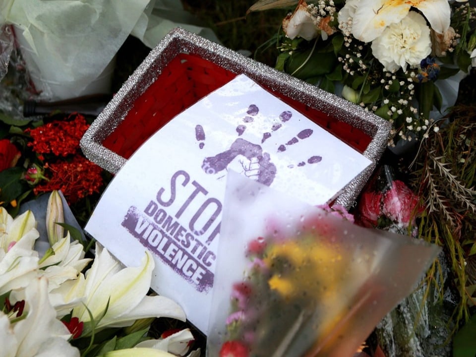 Ein Trauerschrein mit Blumen und einem A4-Blatt mit der Aufschrift «Stop Domestic Violence»