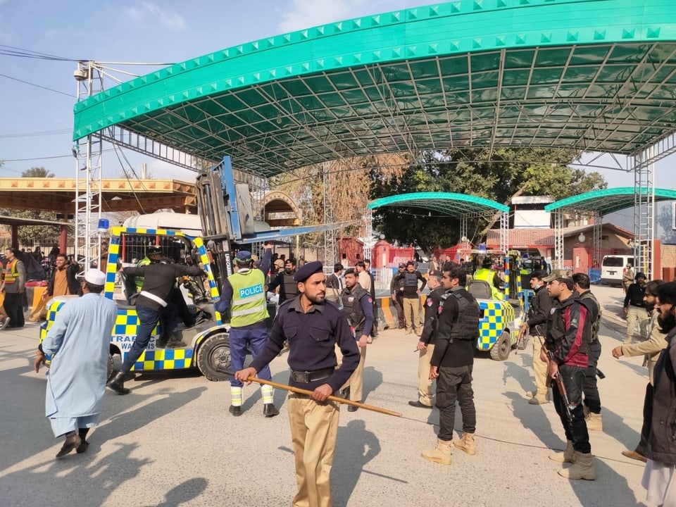 Pakistanische Sicherheitsbeamte stehen Wache, während eine Ambulanz die Opfer wegfährt. 