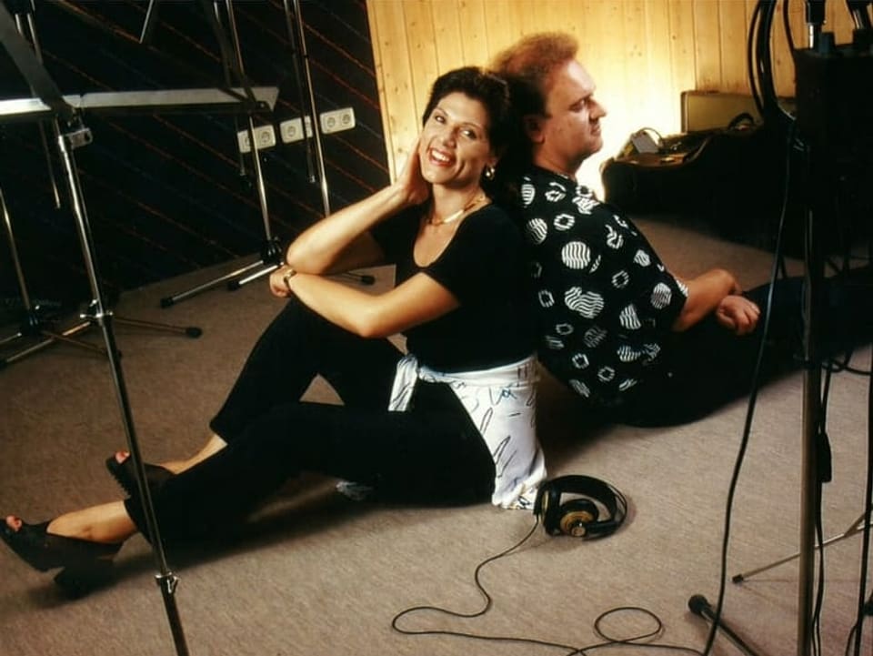 Maja und Carlo Brunner pausieren während Studioaufnahmen am Boden sitzend Rücken an Rücken.
