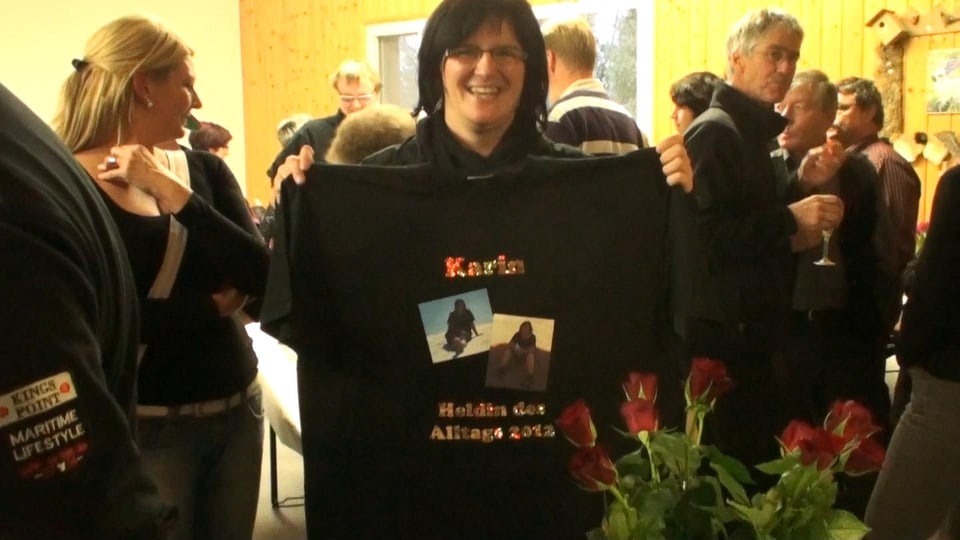 Karin Boss-Röthlisberger hält ein T-Shirt «Helden des Alltags» in den Händen.