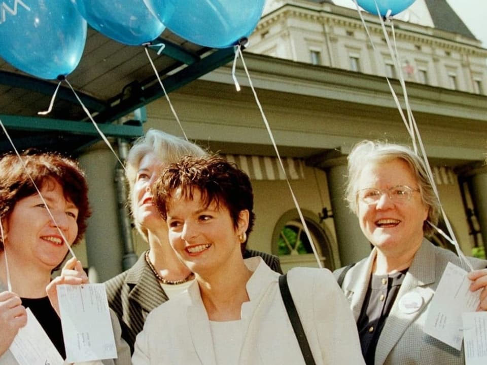 Fünf mittelalte Frauen mit Ballonen in den Händen.