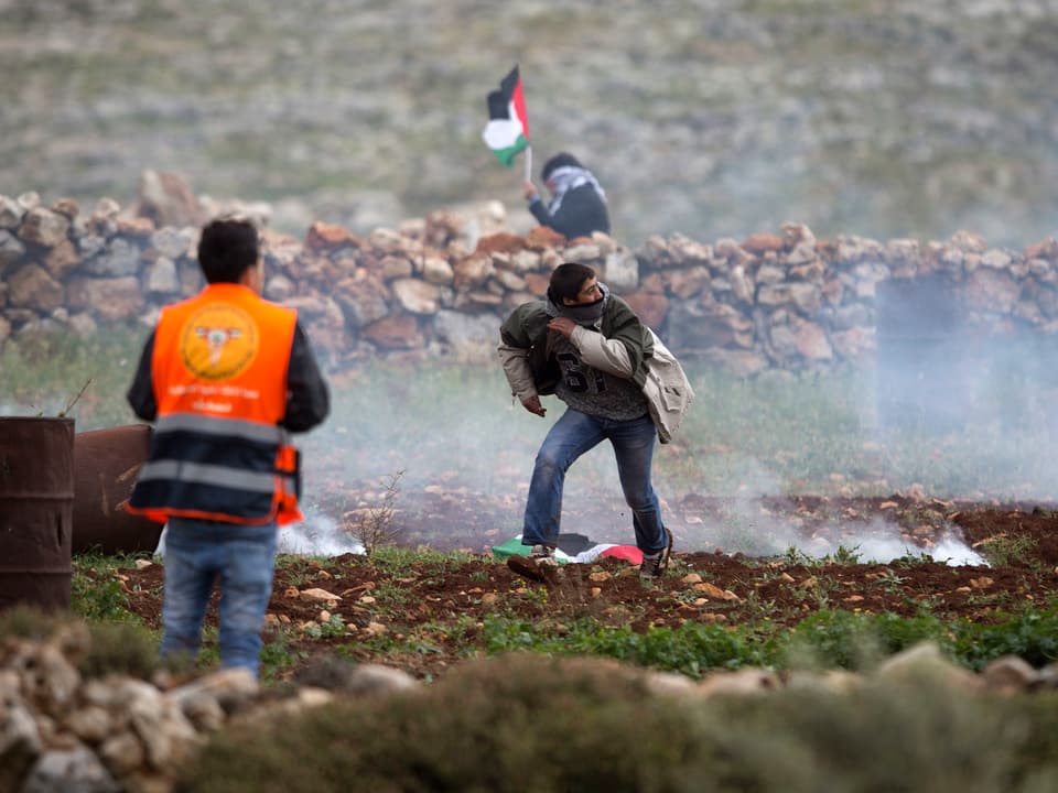 Ein Palästinenser rennt von einer Mauer weg.