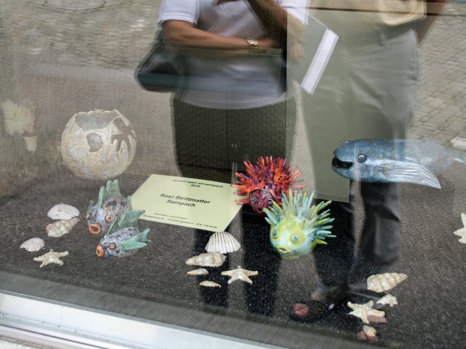 Fischfiguren und Muscheln liegen in einem Schaufenster,.
