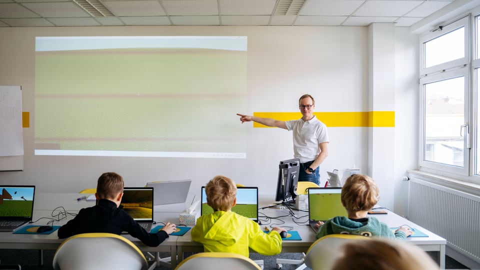 Lehrer unterrichtet Schüler und zeigt auf die Leinwand.