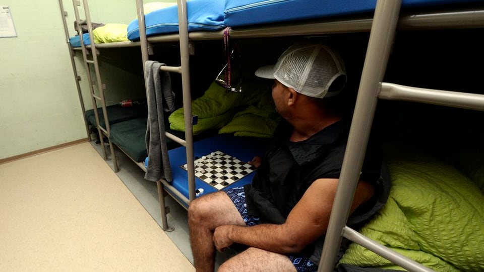Asylbewerber sitzt auf einem Bett in einer Zivilschutzanlage.