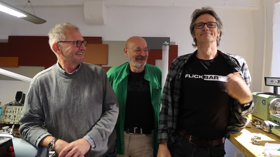 Drei Männer, einer trägt ein T-Shirt mit der Aufschrift "Flickbar"