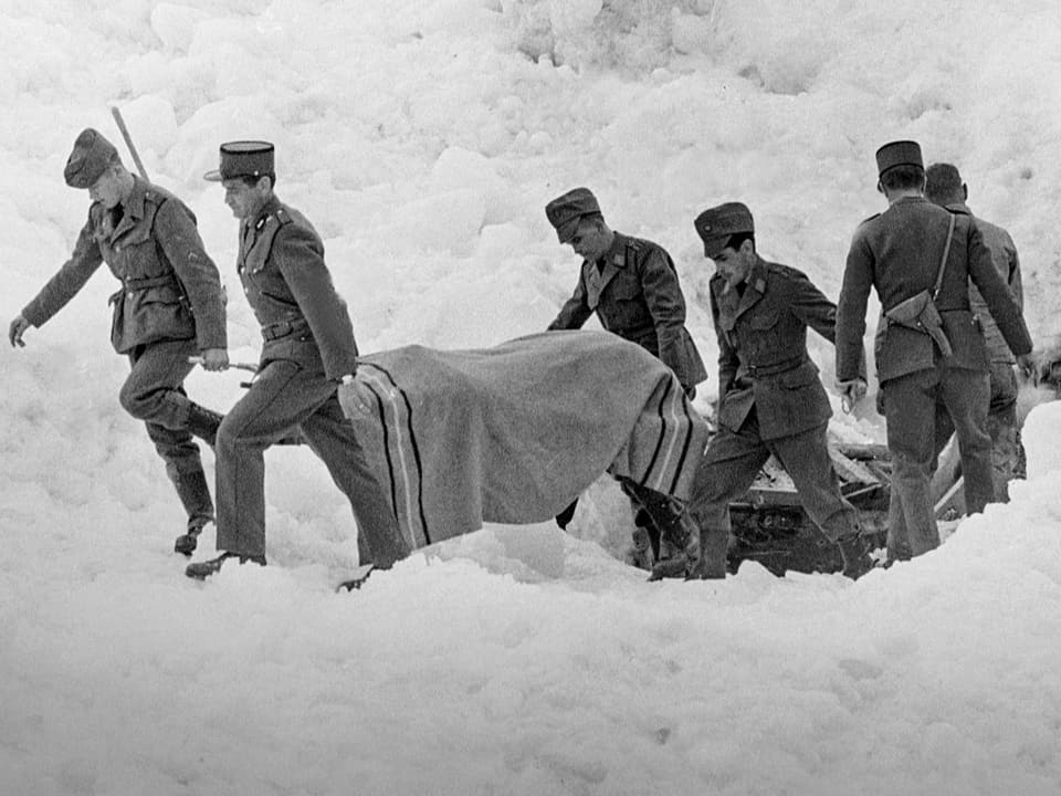 Soldaten tragen eine Bahre aus dem Schnee.