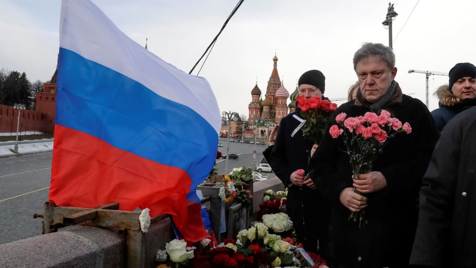Mann mit Blumen und russischer Flagge.
