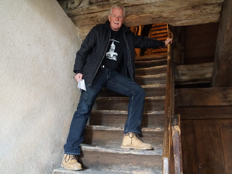 Ein Mann steht mit offener Jacke auf einer Holztreppe.