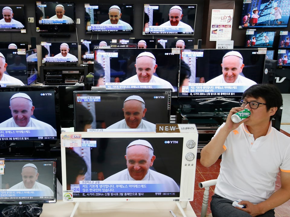 Mehrere Bildschirme zeigen den Papst. 