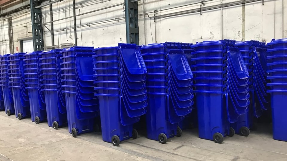 Viele blaue Mülltonnen in einer Halle. 