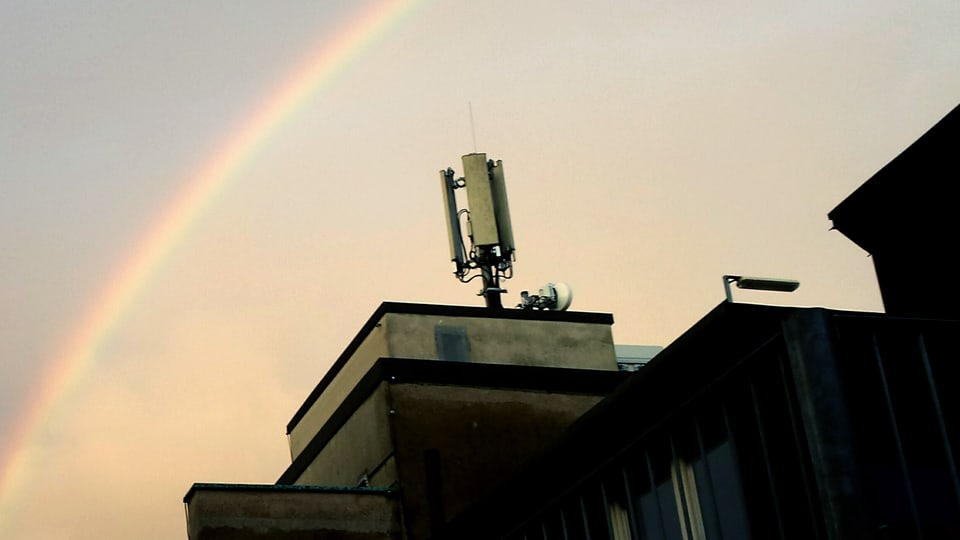 Handyantenne auf einem Dach und Regenbogen.
