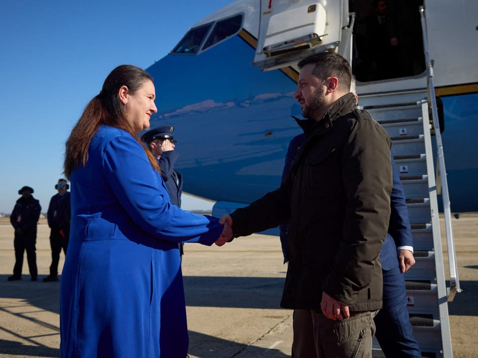 Die Botschafterin trägt einen strahlend blauen Mantel. Selenski trägt eine graue Jacke.