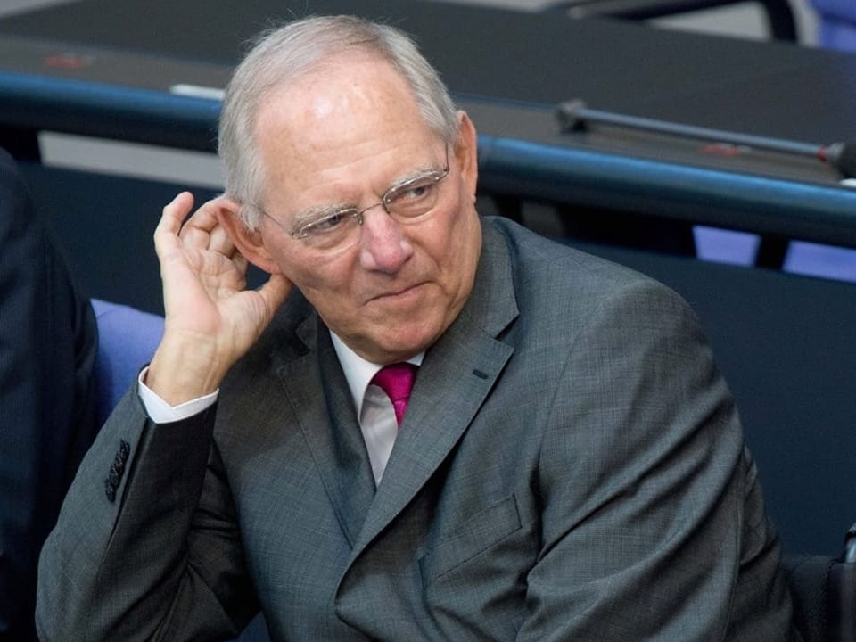 Wolfgang Schäuble sits at a table in the German Bundestag, supporting his right arm.