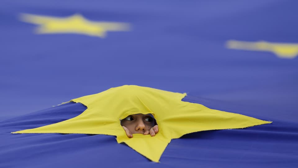 Junge blickt durch einen zerrissenen EU-Stern. 