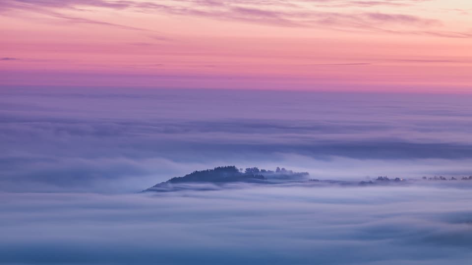 Blick auf das Nebelmeer. Einzelne Hügel ragen als Inseln aus dem Nebelmeer.
