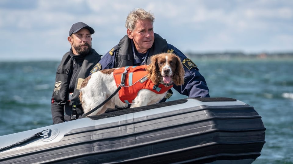 Ein Hund mit zwei Polizisten auf einem Schlauchboot.