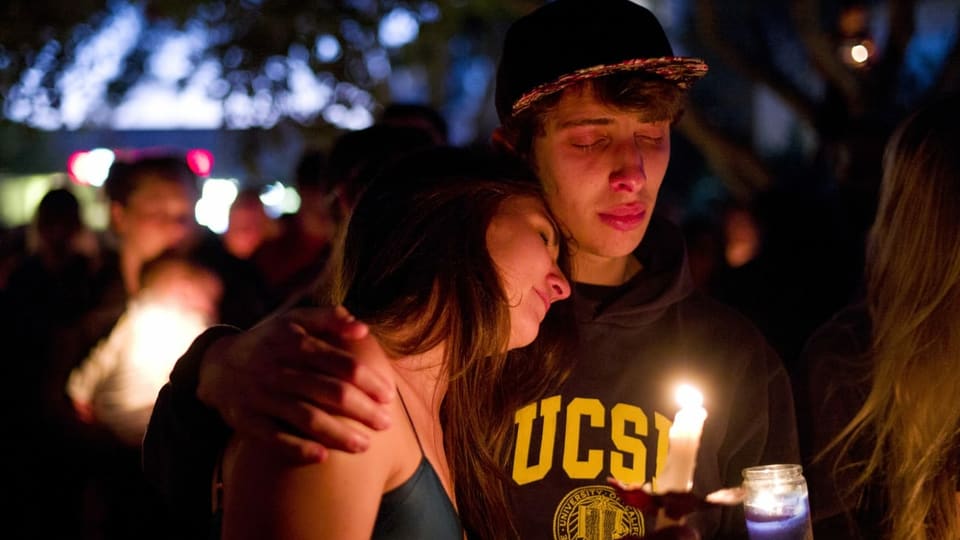 Zwei Teenager, die eine Kerze halten und sich umarmen