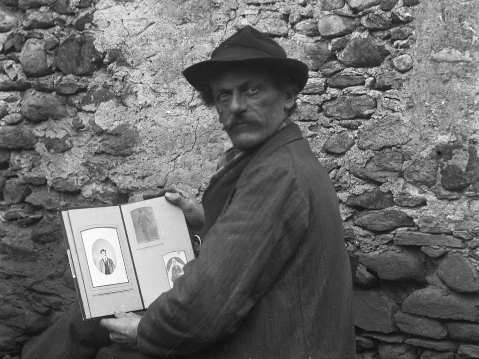 Ein Mann mit Hut und einem aufgeschlagenen Buch in der Hand.