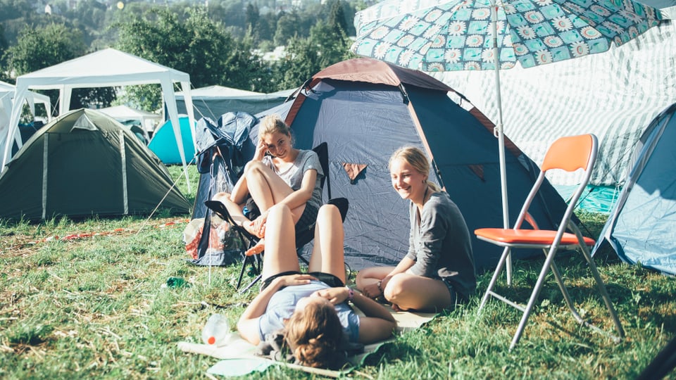 Freundinnen sitzen vor ihrem Zelt