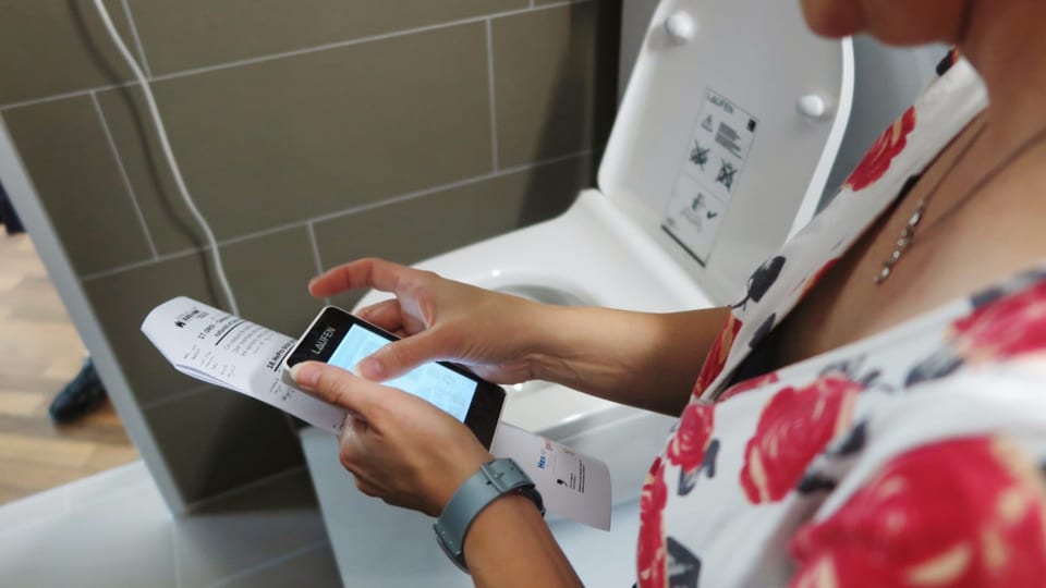 Eine Frau programmiert per App die Toilette. 
